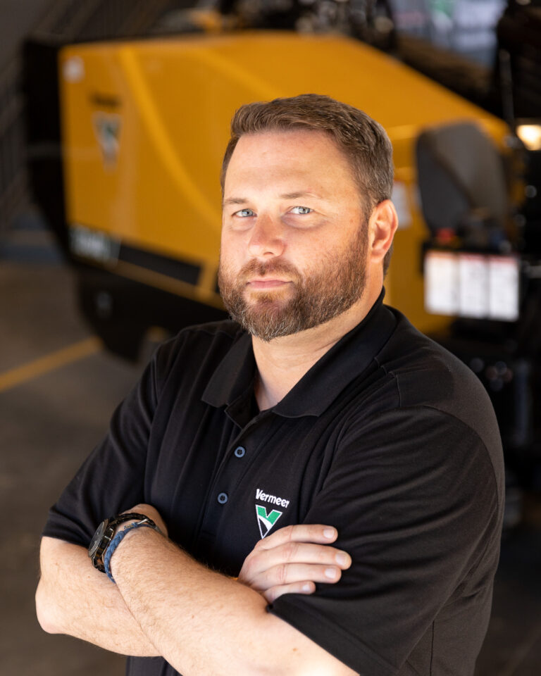 Cory Ray, Vermeer Underground Sales Representative, standing in front of Vermeer machinery.