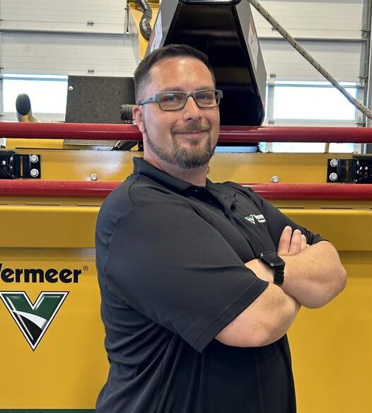 George Piaskowski, Vermeer sales rep, standing in front of a Vermeer Brush Chipper.