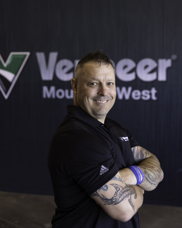 Jason Palanio, Vermeer Equipment Sales Representative, standing in front of Vermeer logo.