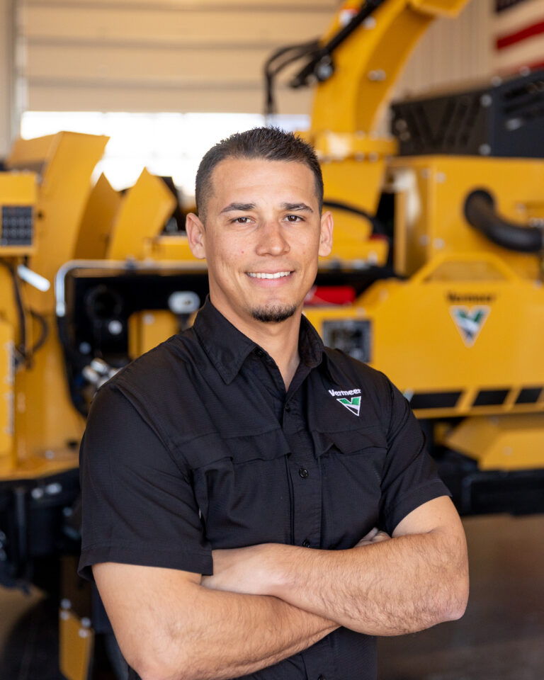 Nikko Baca, Vermeer Environmental Sales Representative, standing in front of Vermeer machinery.