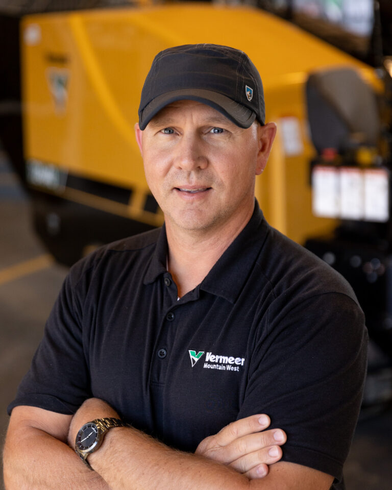 Rory Collins, Vermeer Underground Sales Representative, standing in front of Vermeer machinery.