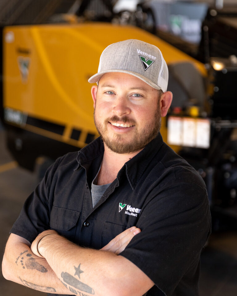 Ryan Phillips, Vermeer Underground Sales Representative, standing in front of Vermeer machinery.