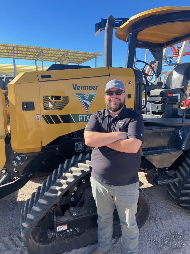 Carlos Charles, Vermeer Borestore Rep, standing arms crossed in front of Vermeer machinery.