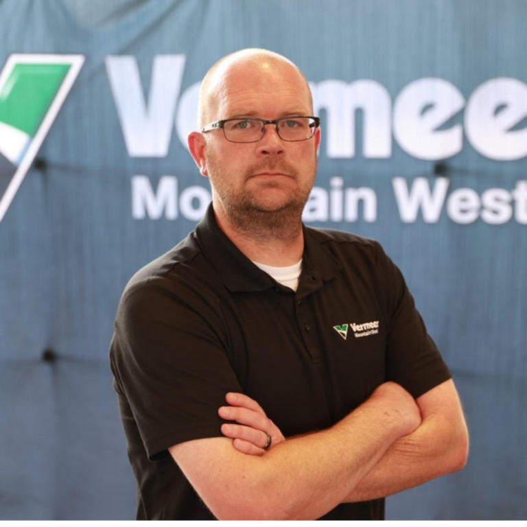 Clinton Shepherd, Vermeer Service Manager in Las Vegas, standing arms crossed in front of a black Vermeer backdrop.