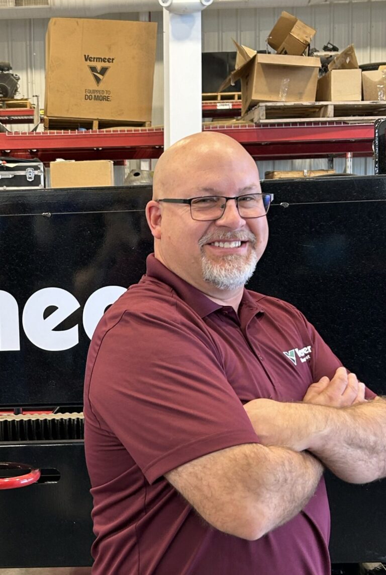 Karl Lorenz, Vermeer Mountain West Service Manager standing with arms crossed in front of Vermeer machinery.