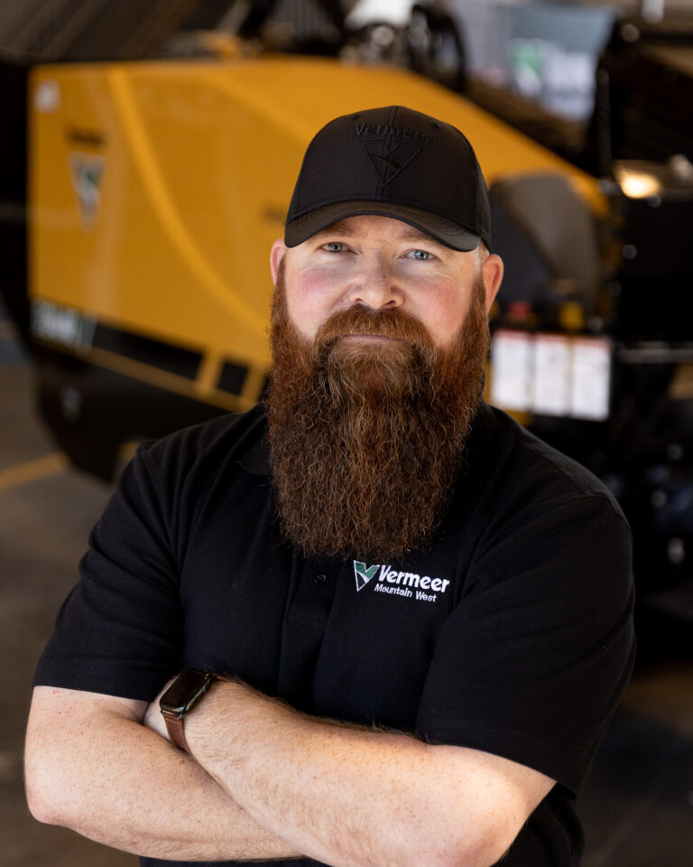 Sam Ashbrook, Vermeer Mountain West Borestore Specialist stands with arms crossed in front of Vermeer Machinery.